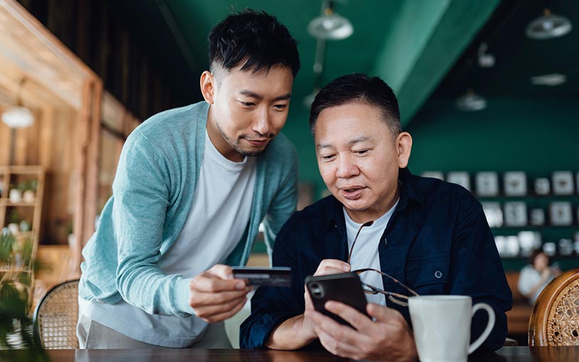 Two men looking at a credit card and a phone