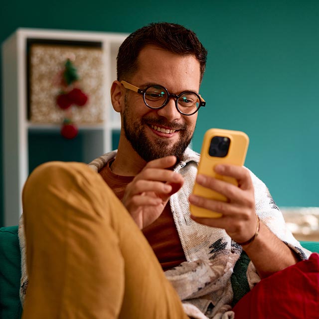 Guy looking at his phone on the couch at home.