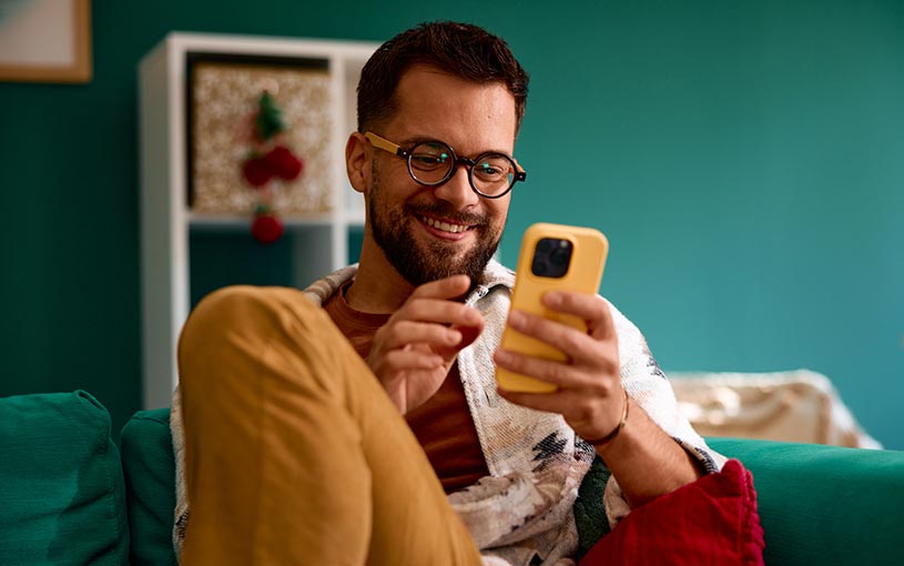 Guy looking at his phone on the couch at home.