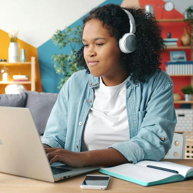 Girl using a laptop sitting at her desk.