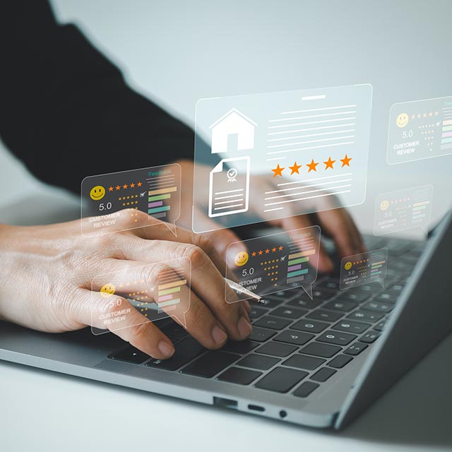 A person's hands typing on a laptop with homes and reviews in pop ups.