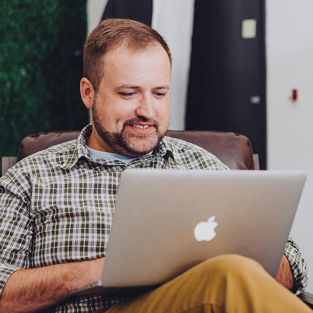 Man using his laptop sitting in a chair