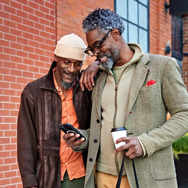 Male couple looking at their phone holding shopping bags